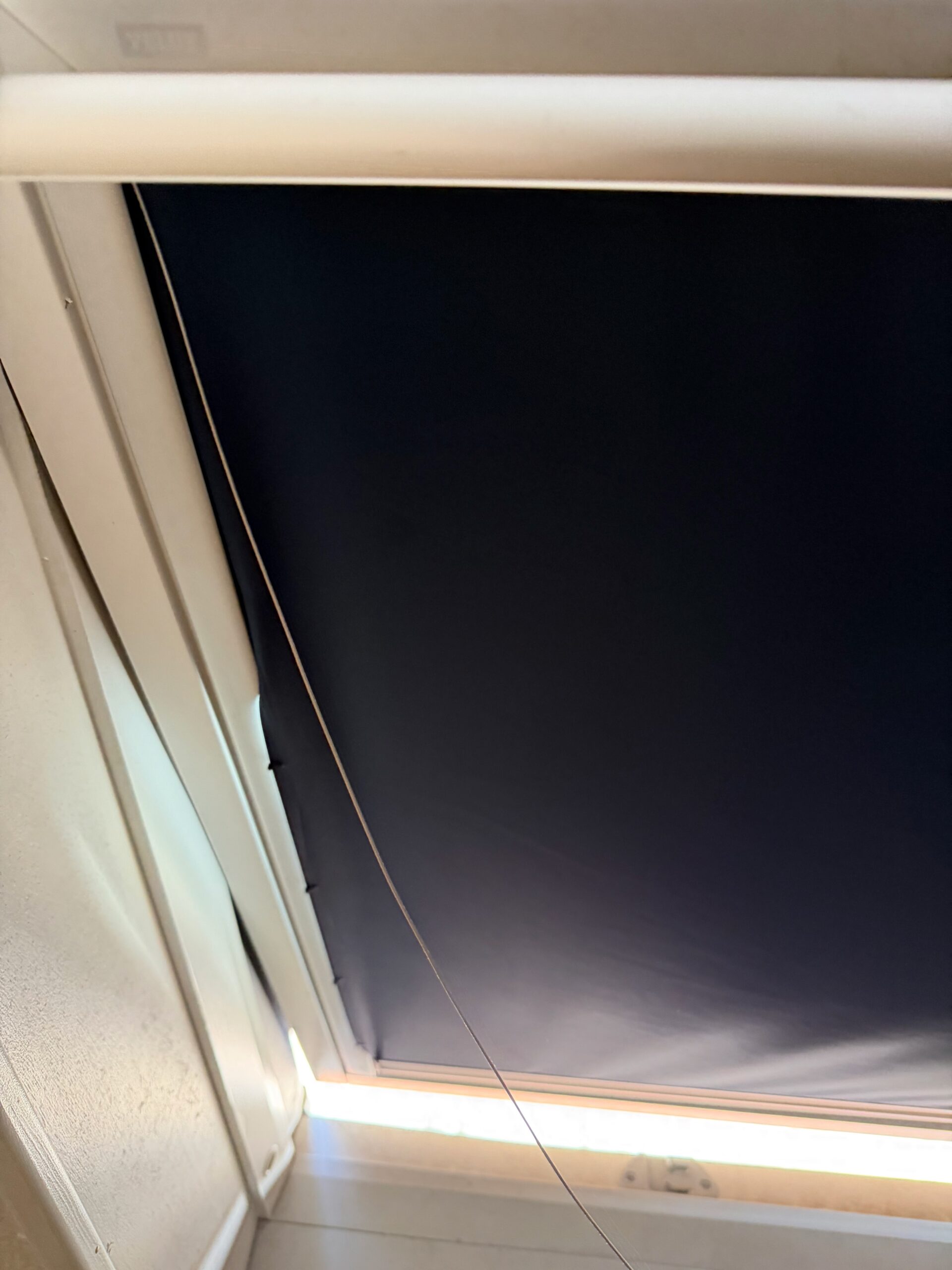 Store occultant Velux cassé : toile affaissée et câbles de guidage détendus.