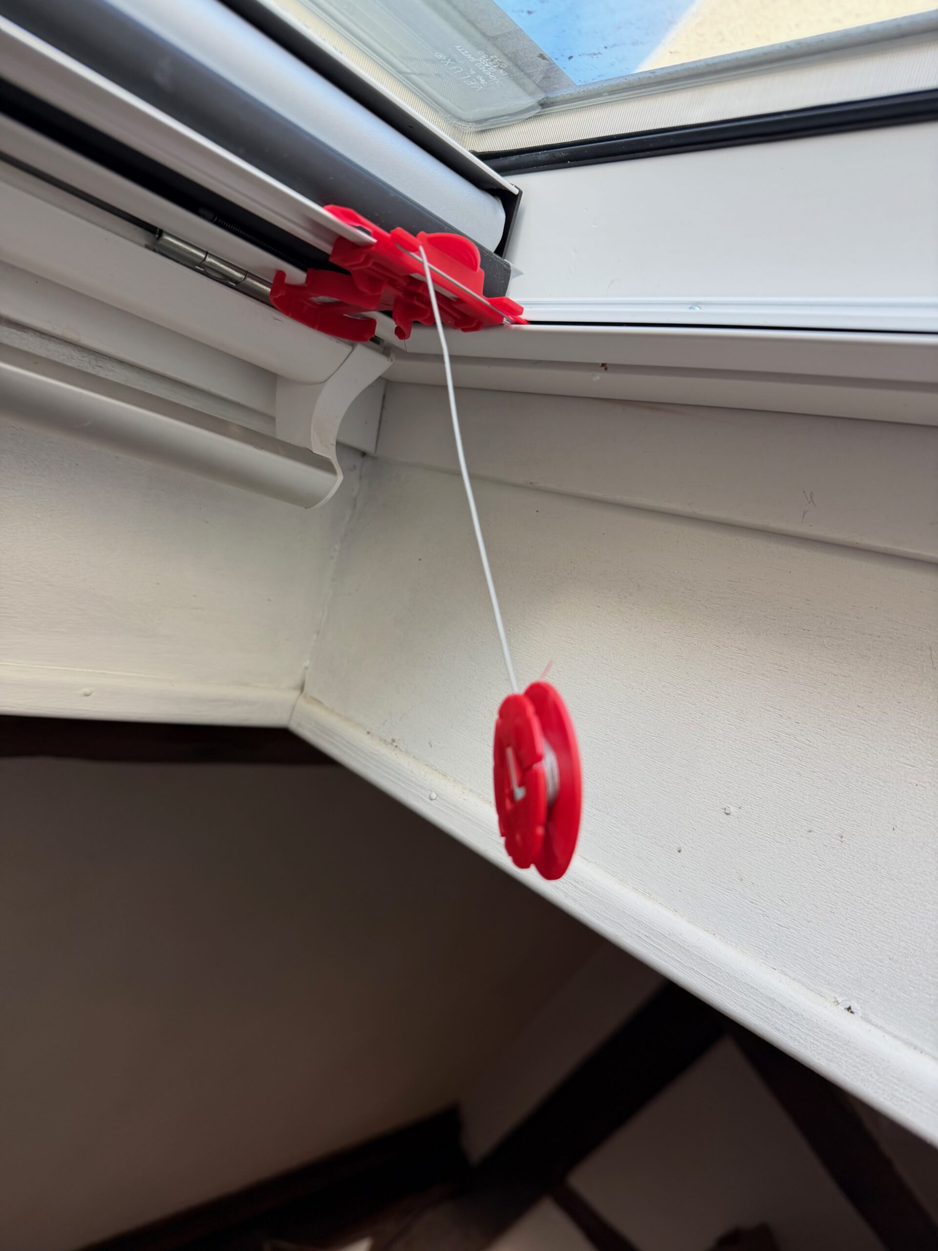 Pose du nouveau store : câbles de tension maintenus par les enrouleurs rouges de montage.