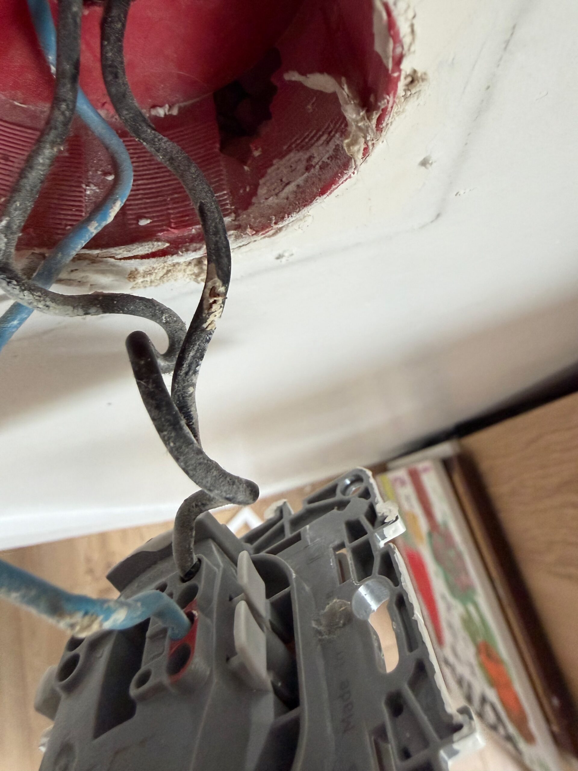 Fils électriques noircis et carbonisés dans un boîtier d'interrupteur, conséquence d'un arc électrique.