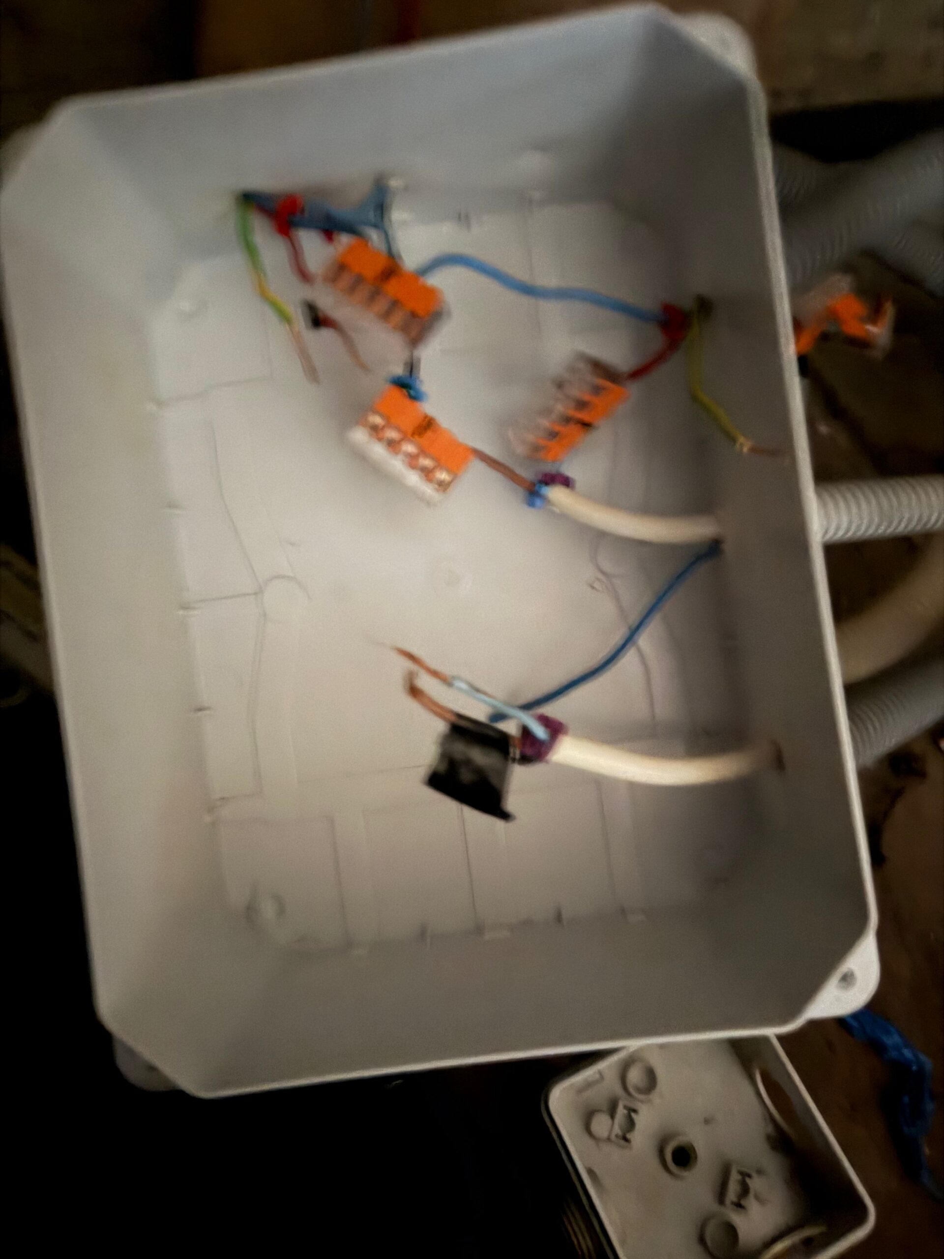 Boîtier de dérivation électrique ouvert avec connecteurs Wago orange en cours de raccordement.