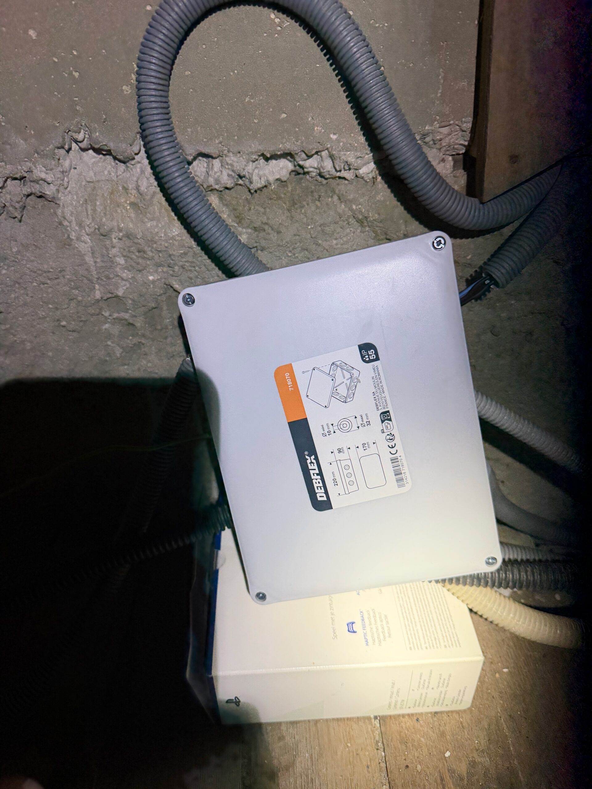Nouveau boîtier de dérivation électrique étanche IP55 vissé au mur, avec gaines raccordées.