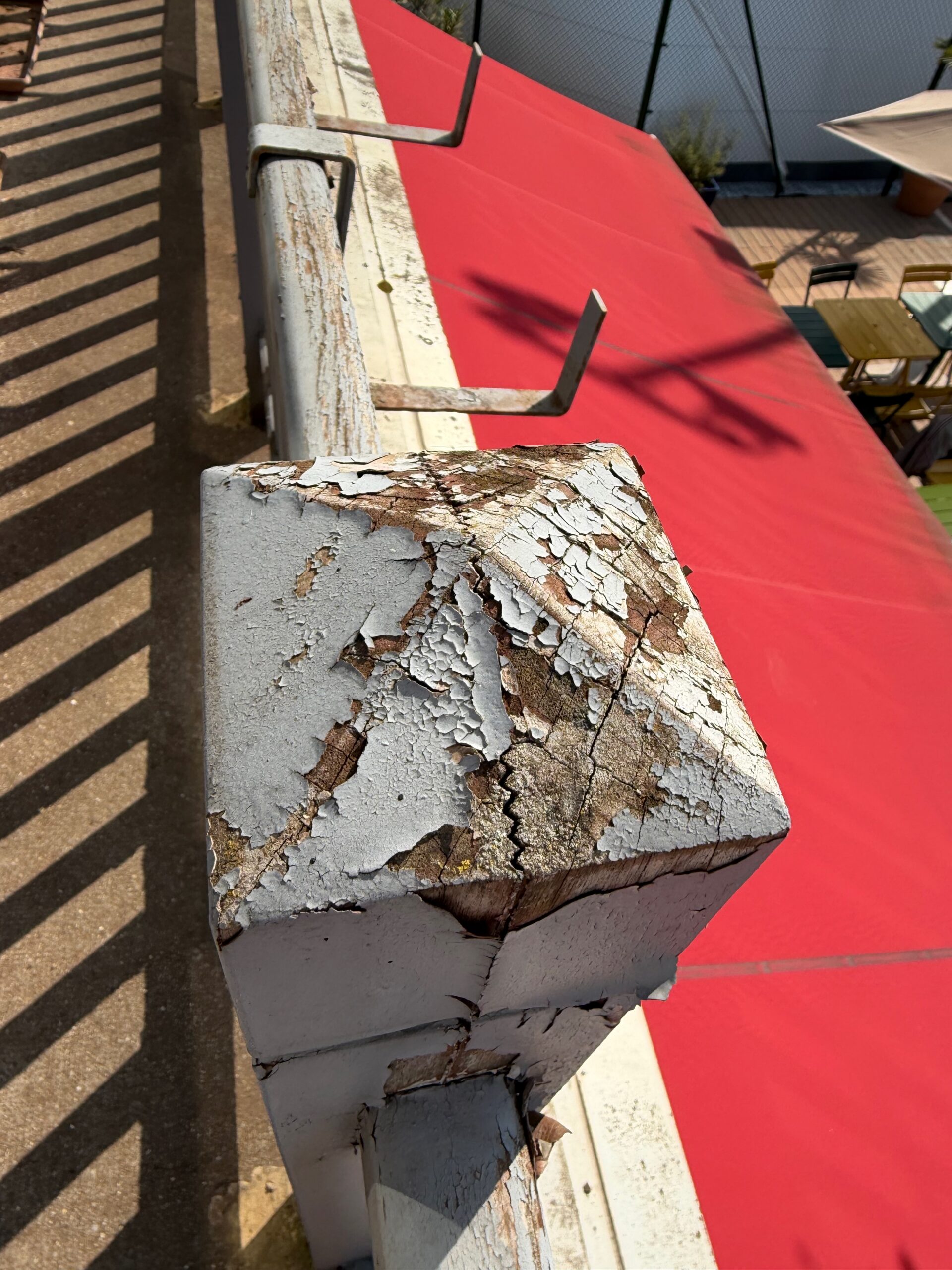 Pilier de la balustrade en bois vu de dessus avant restauration, peinture écaillée, bois fendillé par l'exposition à la pluie et au soleil, club de tennis Saint-Mandé