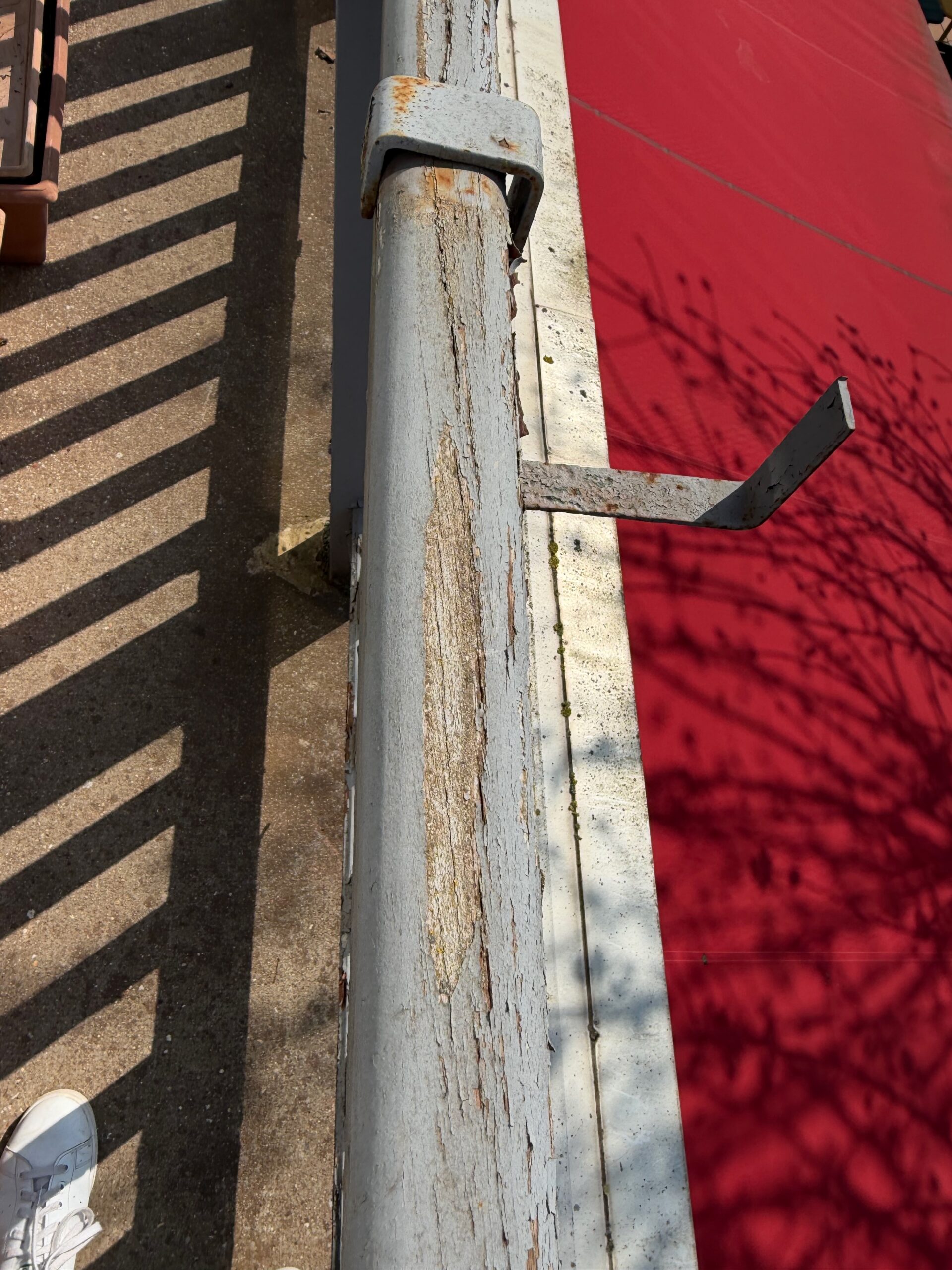Balustrade en bois vue de dessus avant restauration, peinture écaillée se détachant du support, bois fendillé par l'exposition à la pluie et au soleil, club de tennis Saint-Mandé